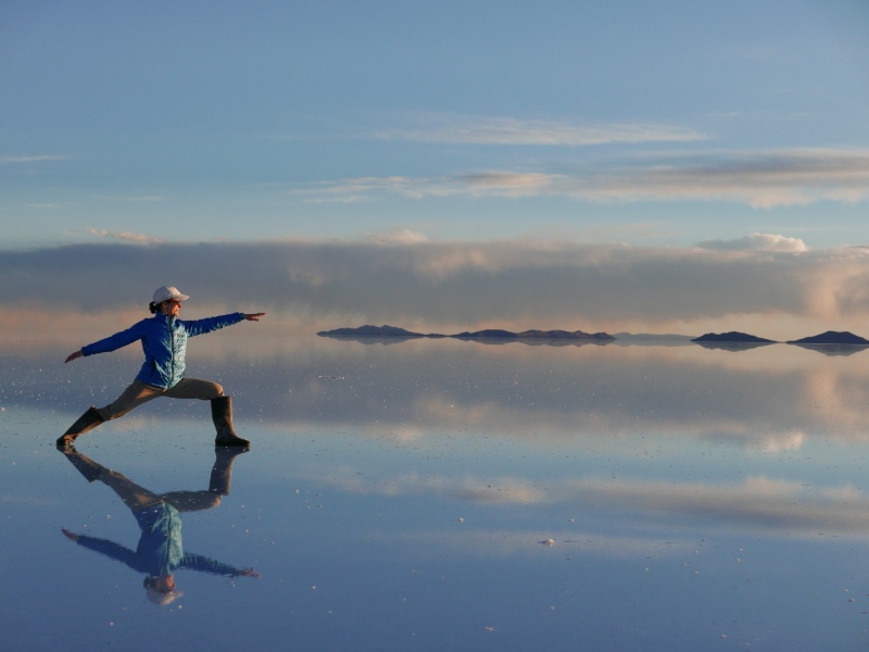 lori weinstock strikes a warrior yoga pose on reflective ice
