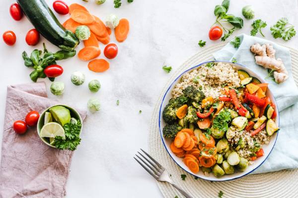 brightly colored vegetable and quinoa bowl surrounded by nutritious ingredients